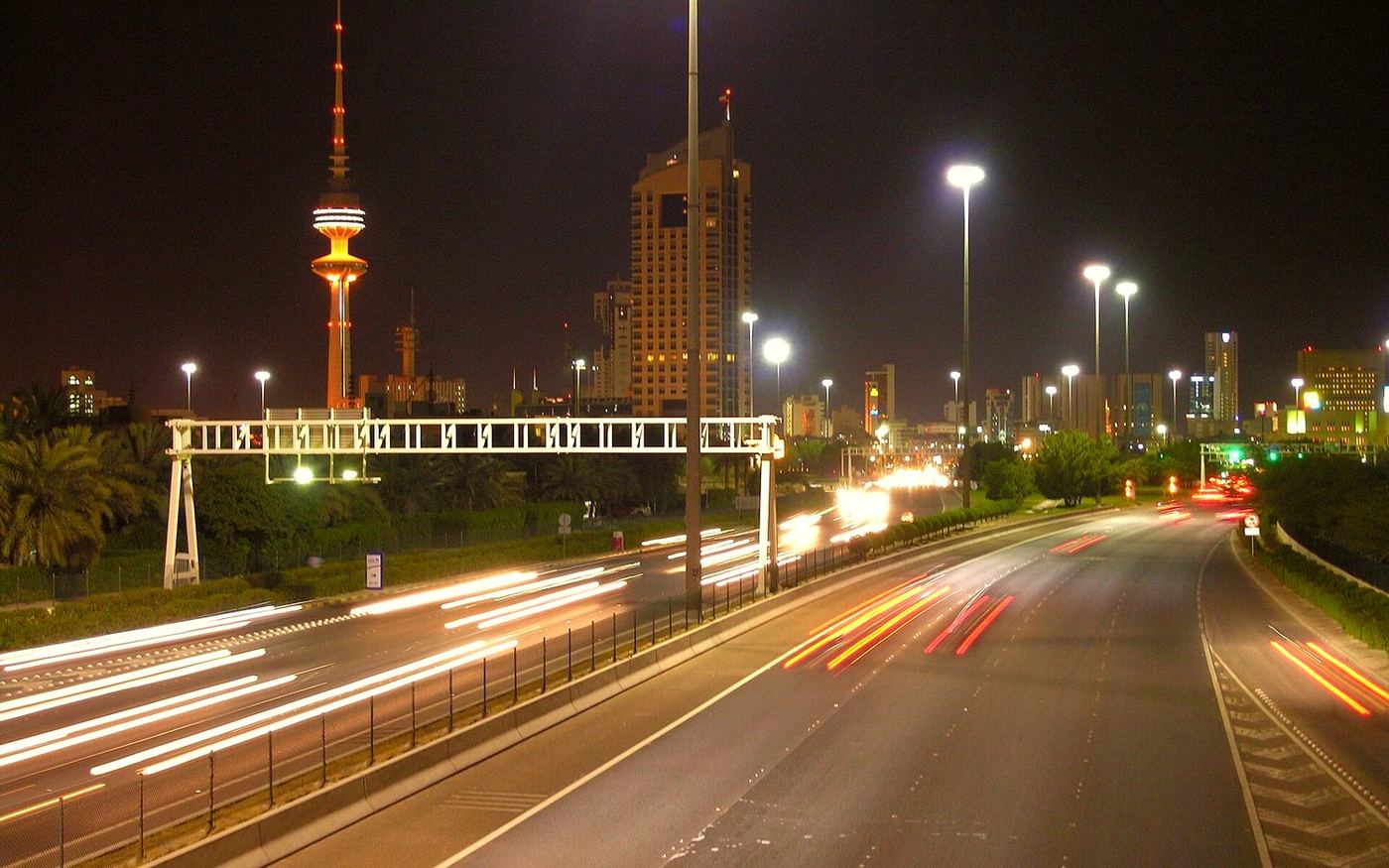 طريق ليلي في الكويت وخطوط ضوء السيارات أمام أبراج المدينة
